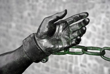 Bronzehand mit Handfesseln, die an einer Kette befestigt ist.