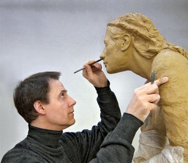 Der Künstler Lutz Gaede formt eine Skulptur einer Frau aus Ton. Bildhauer bei der Arbeit.